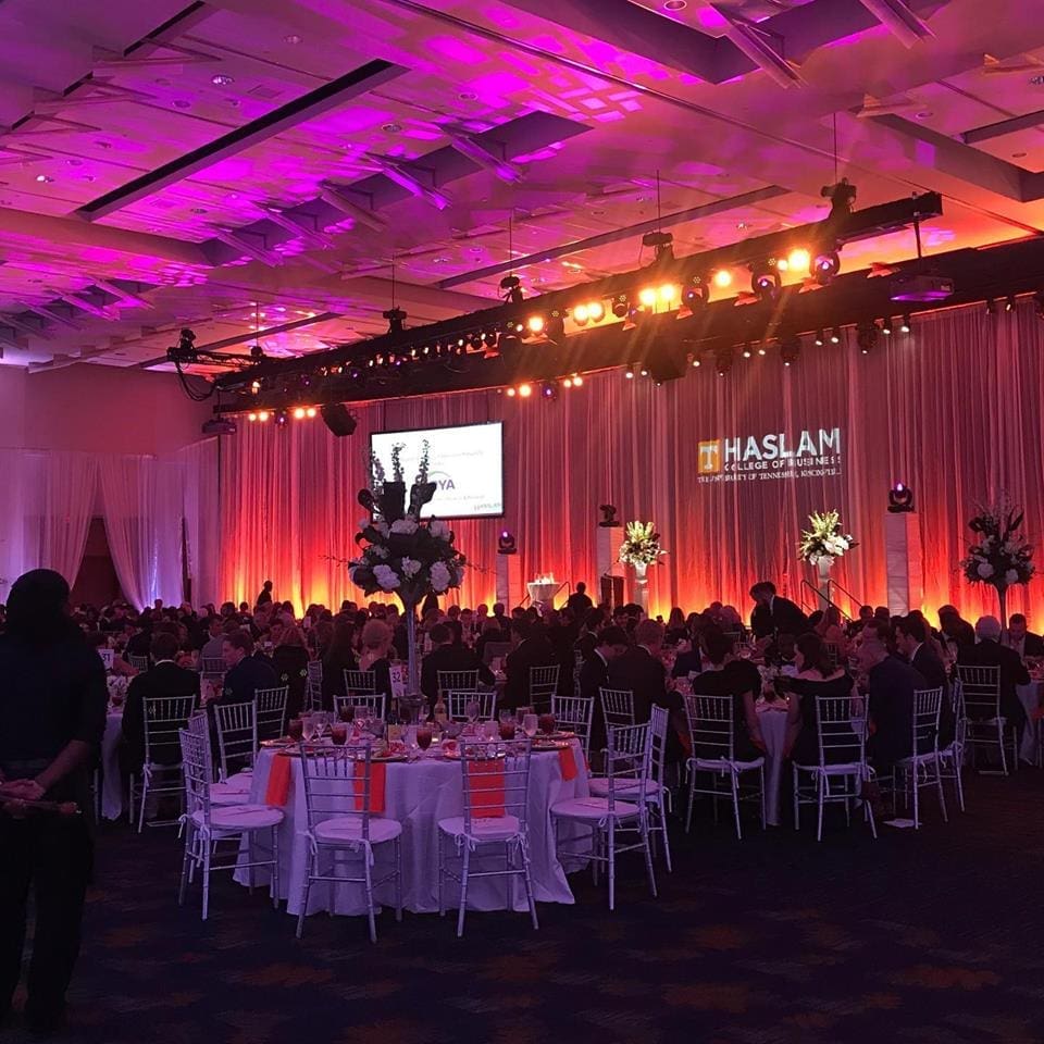 Elegant banquet hall with purple and orange lighting for an event.