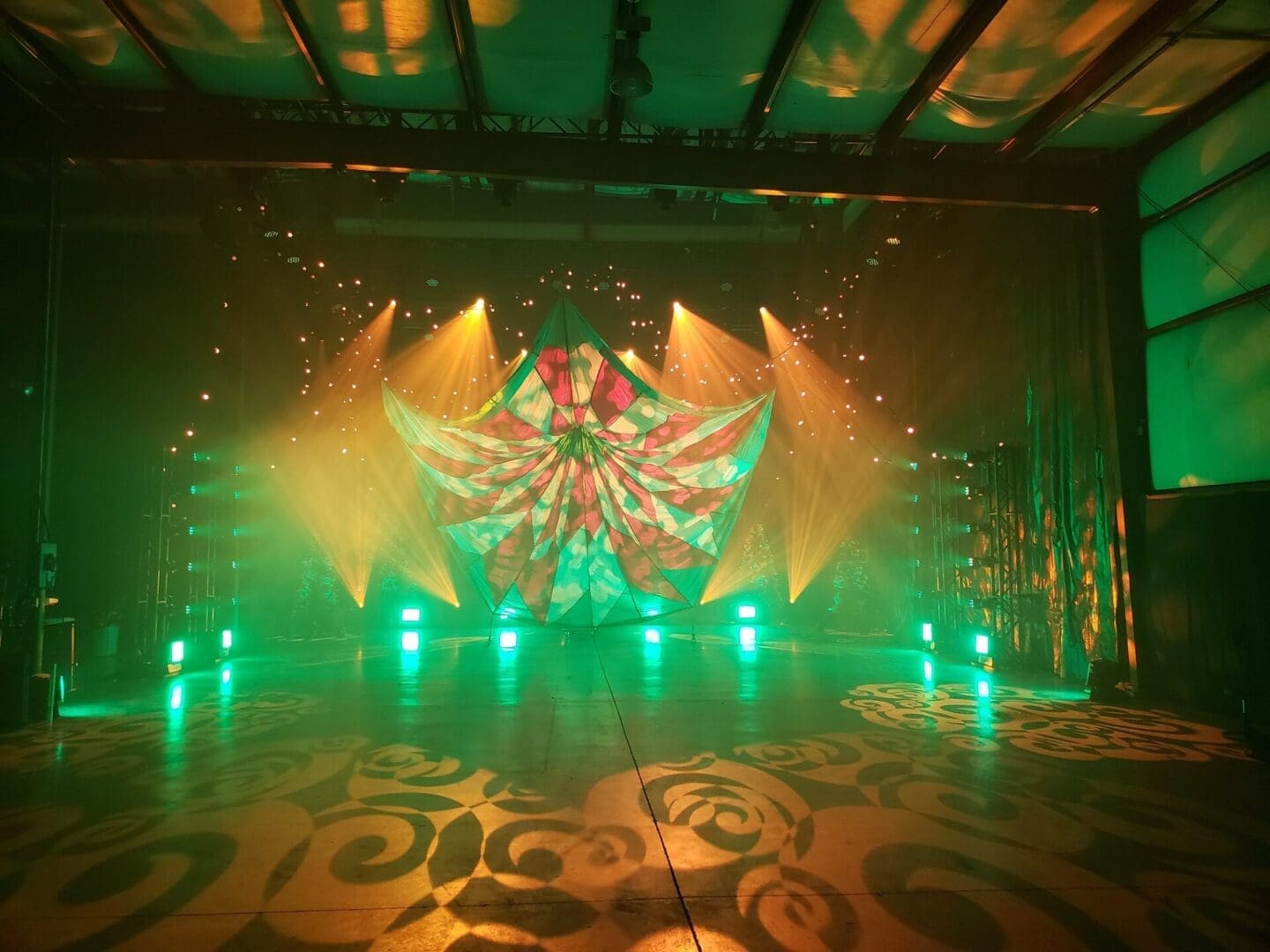 Colorful stage lights and geometric projections create a vibrant atmosphere.