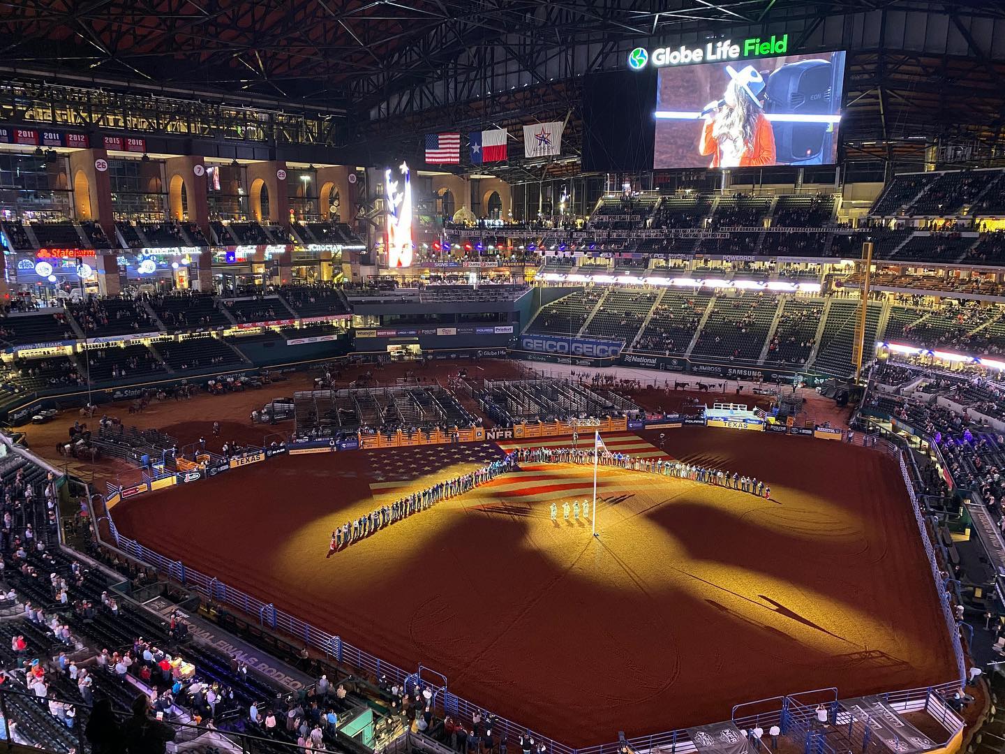 Large indoor arena set up for a rodeo event with dirt floor and rodeo equipment.