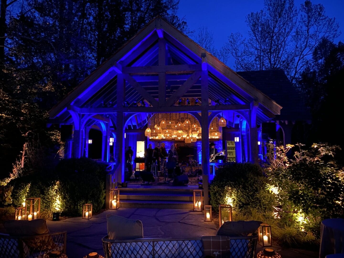 Cozy outdoor pavilion illuminated with warm blue and golden lights at night.