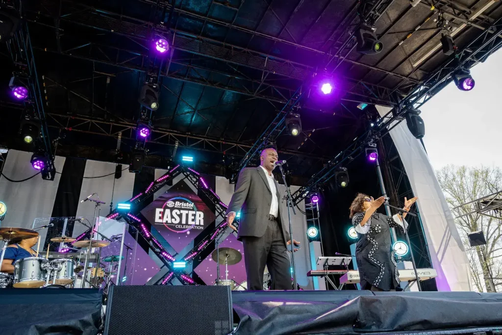 A man and woman singing on stage at an outdoor event.