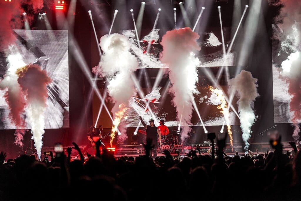 A group of people on stage with smoke coming out of their mouths, featuring HARDY and Bandit Lites.
