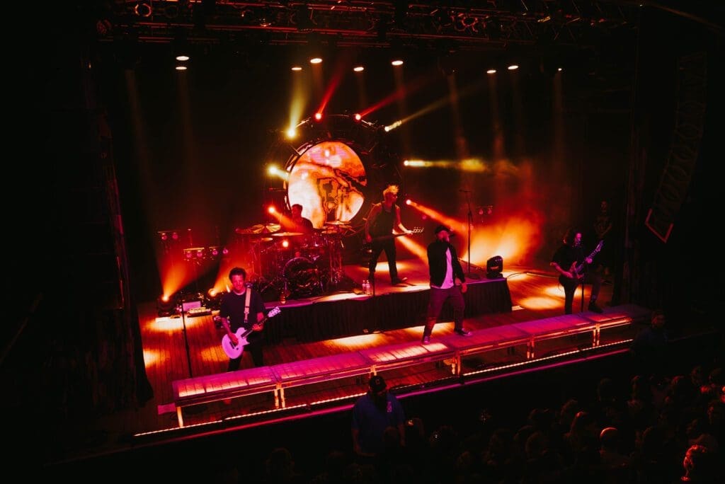 A band performs on stage with vibrant orange and red lighting effects.