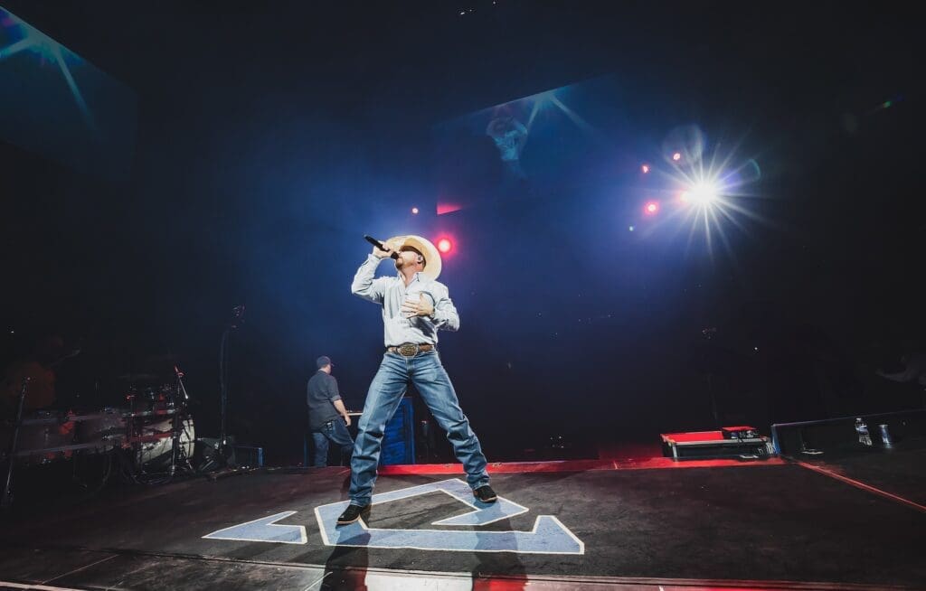 Singer passionately performs on stage with dramatic lighting.