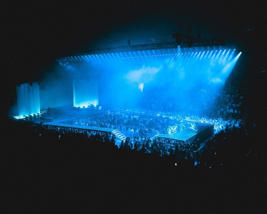 A vibrant concert with blue lighting and a large crowd.