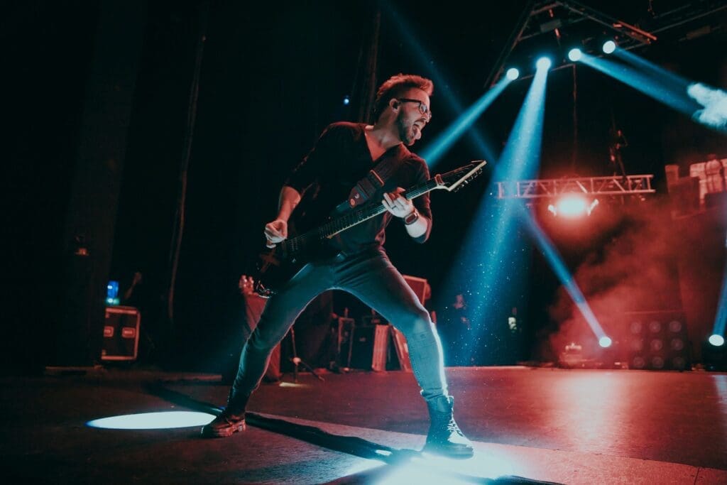 Musician intensely playing guitar on stage with dynamic lighting.