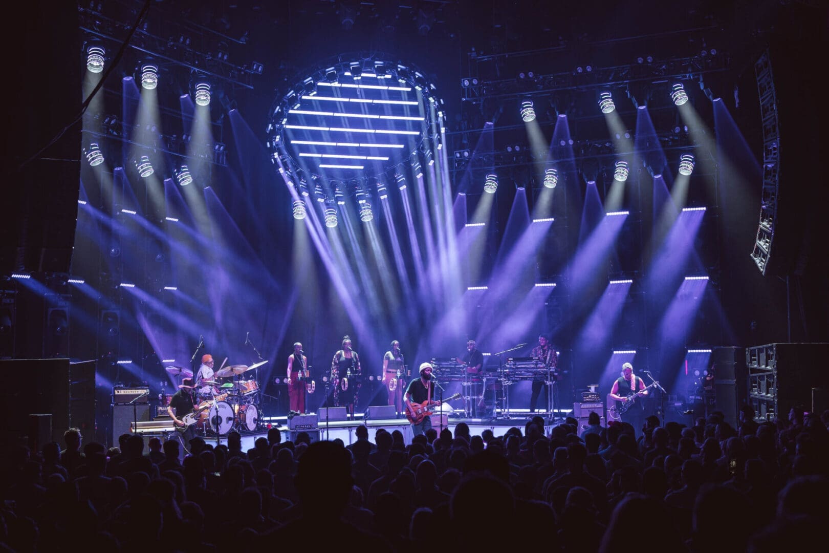 A band performing live on a stage with vibrant blue lighting.