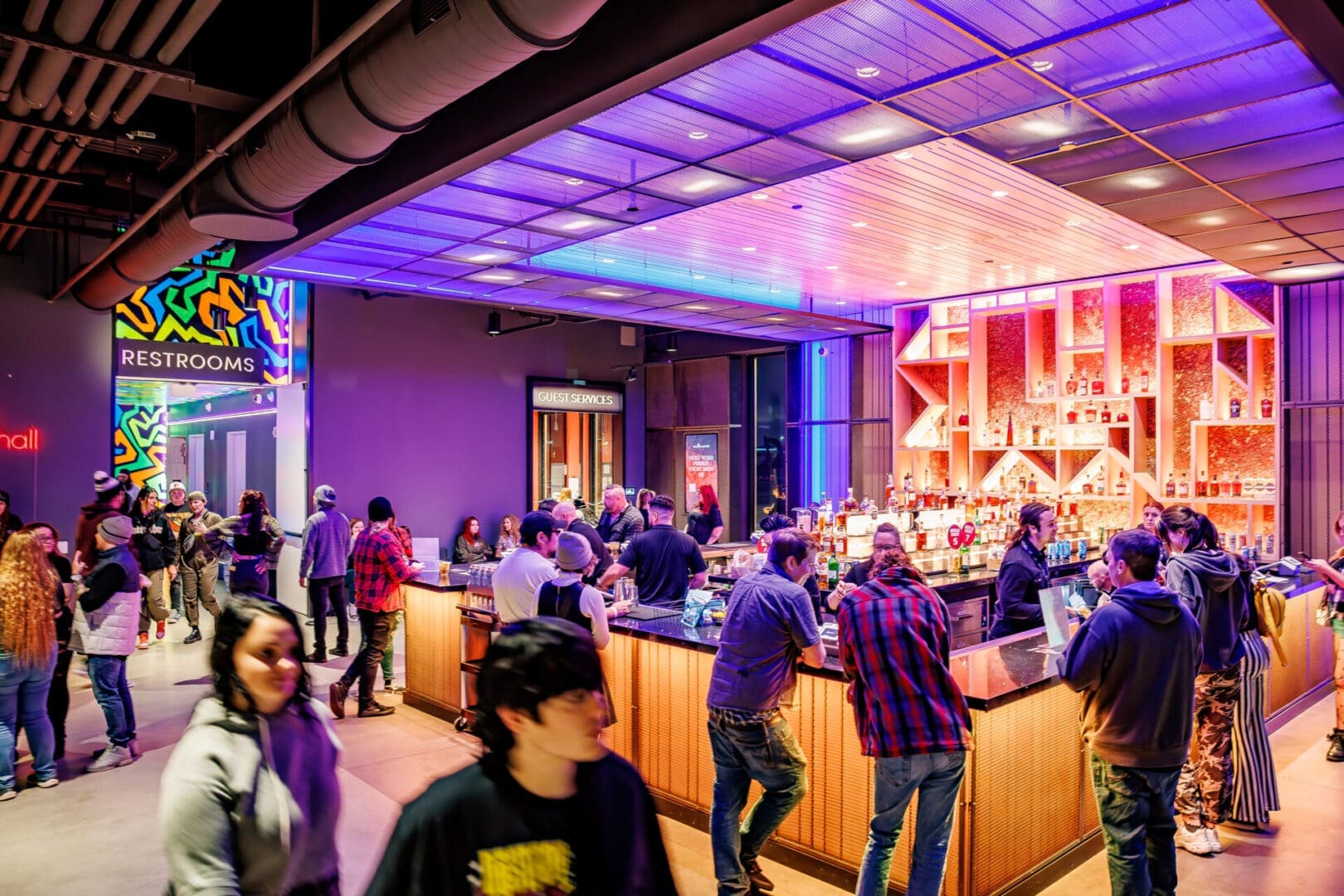 People socializing in a vibrant bar with colorful lighting.