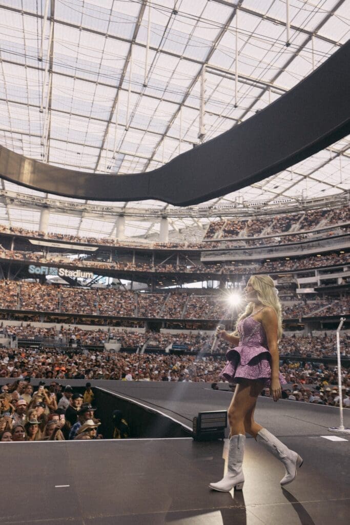 A performer shines under stadium lights in front of a massive crowd.