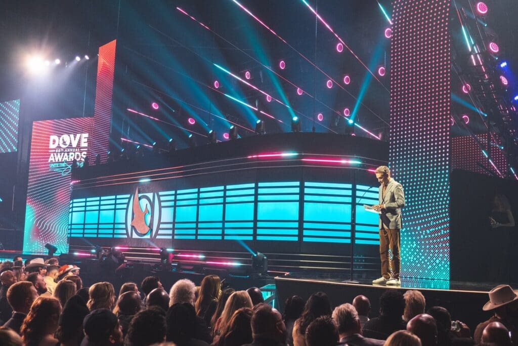 A performer on stage with vibrant lighting and a large audience.