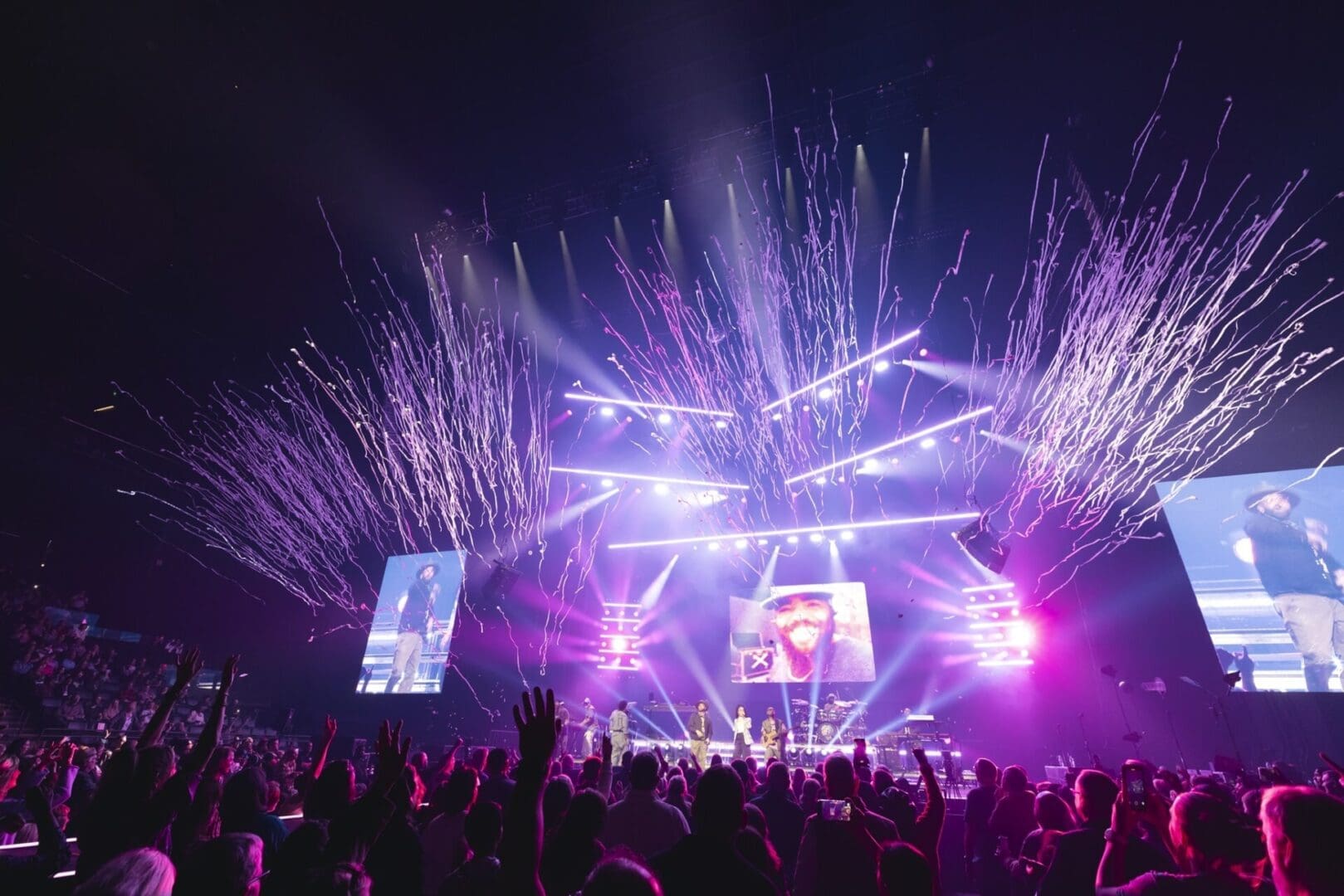 Vibrant fireworks light up a concert stage with an enthusiastic crowd.