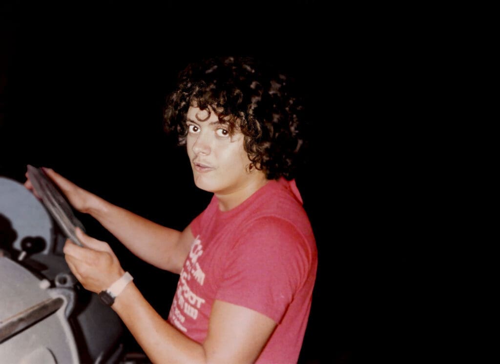 Young man with curly hair wearing a red shirt looking back.