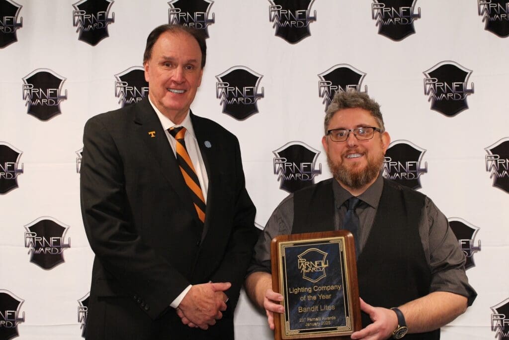 Two men at an award ceremony, one holding a plaque.