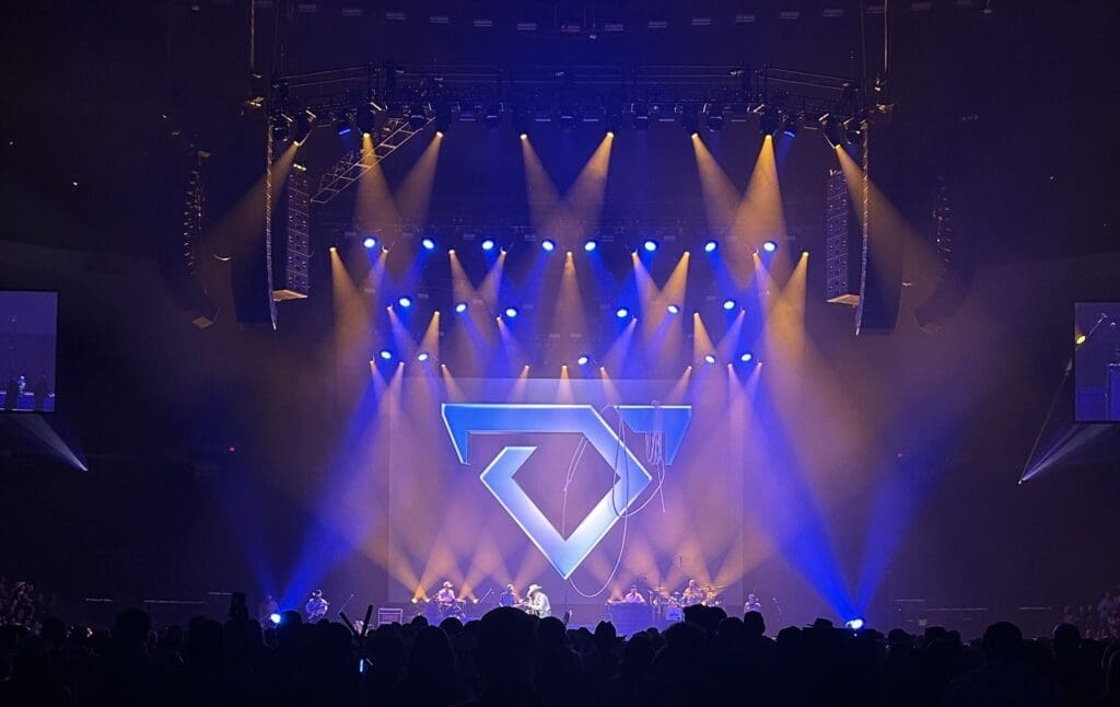 Concert stage with vibrant blue and orange lights and a geometric design.