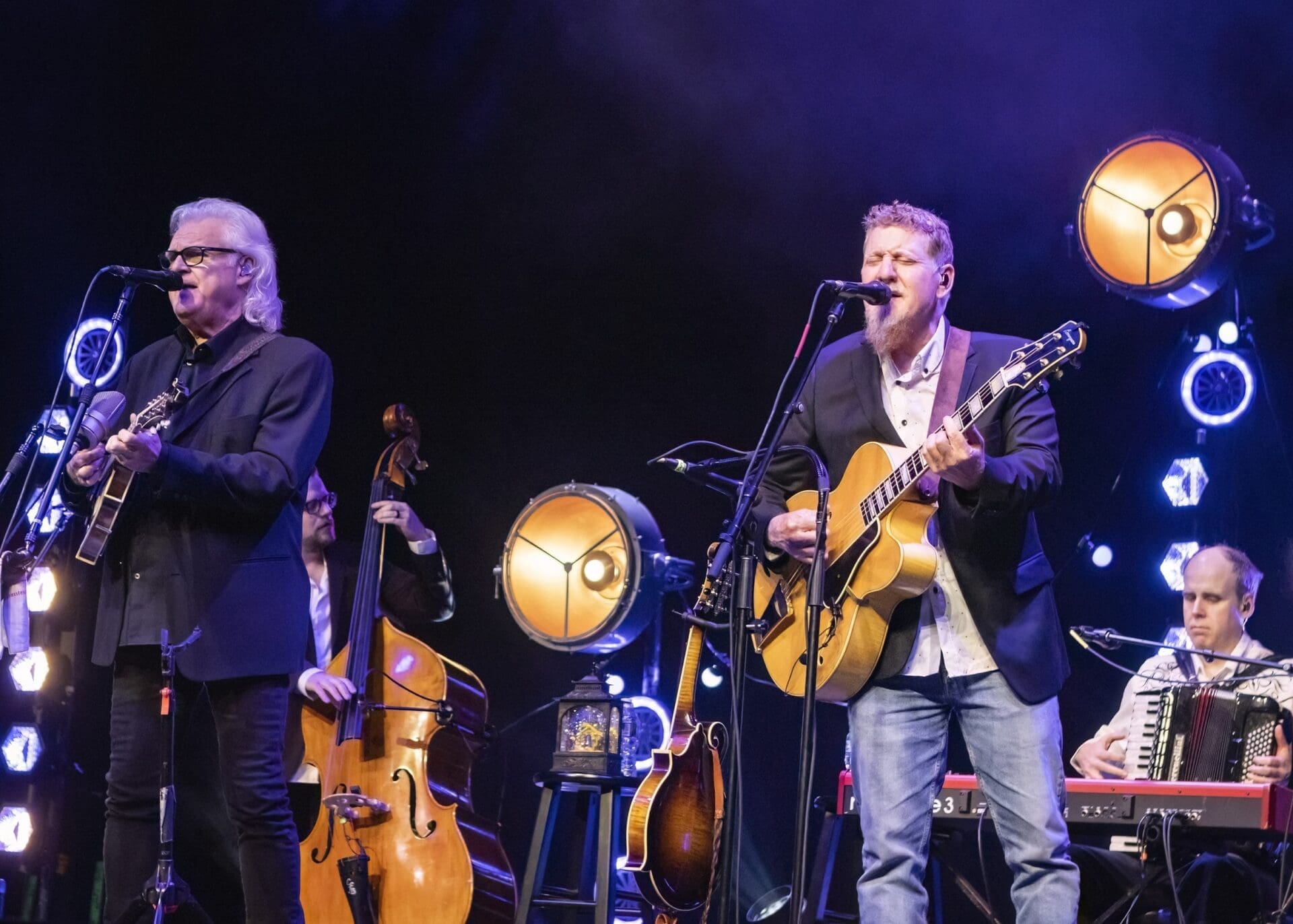 Two musicians performing on stage with guitar and double bass under warm lighting.