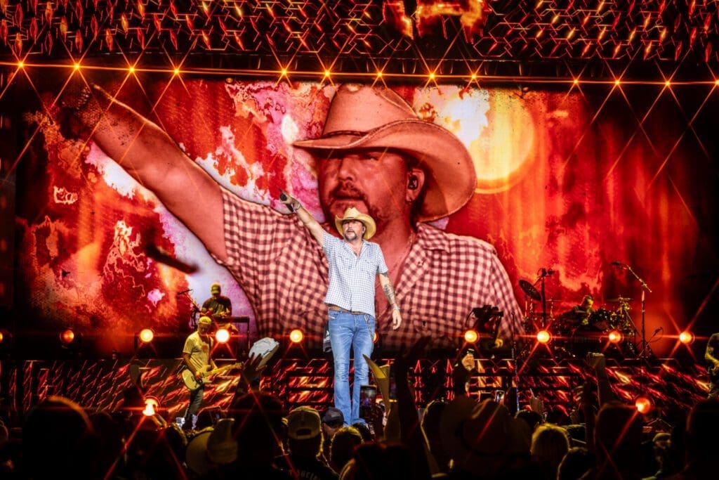 A cowboy performer entertains a lively crowd under festive lights.