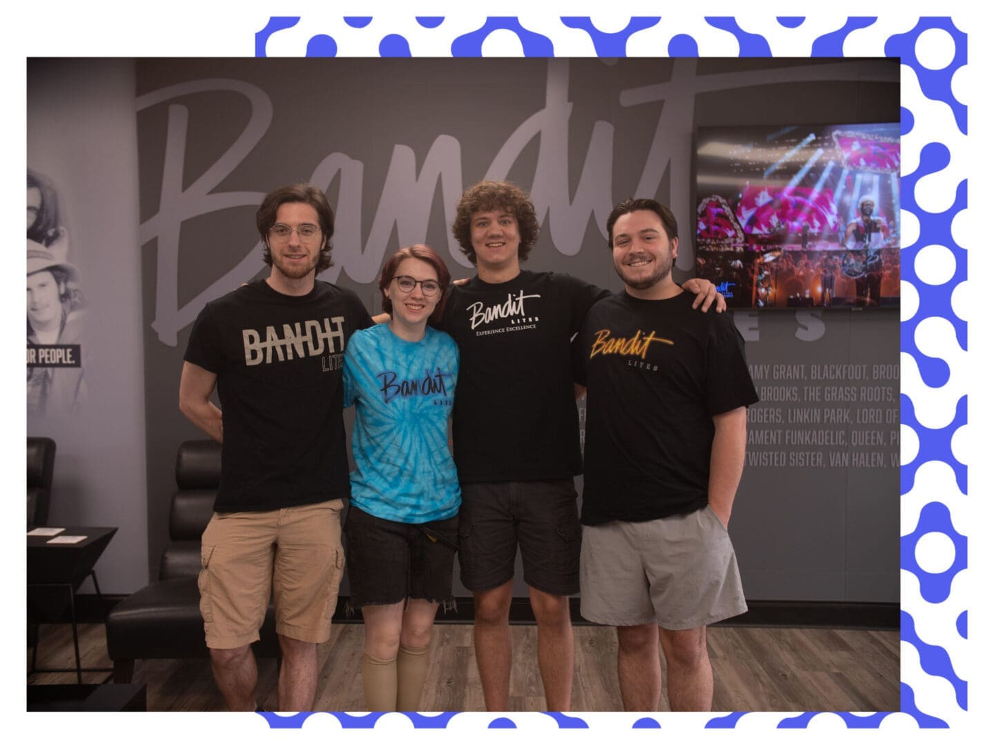 Four friends posing together, smiling indoors at a casual event.