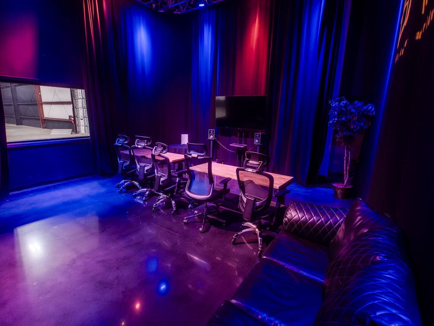 Dimly lit lounge with musical instruments and cozy seating under blue and purple lights.