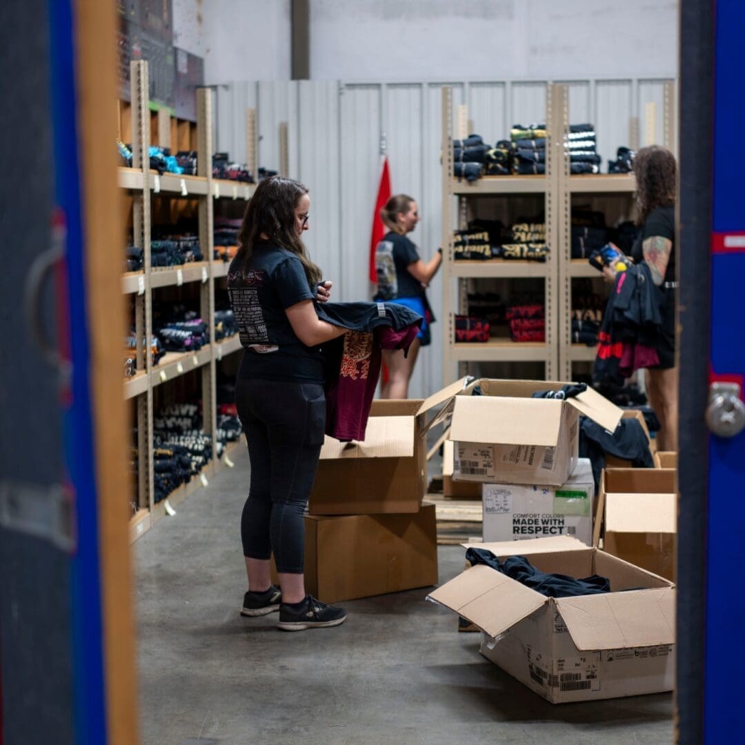 Person organizing and packing items in a storage room filled with shelves and boxes.