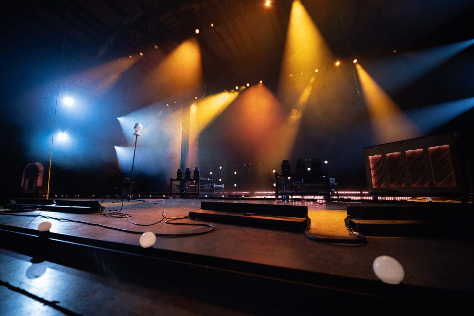 Empty stage lit with dramatic spotlights and fog effects.