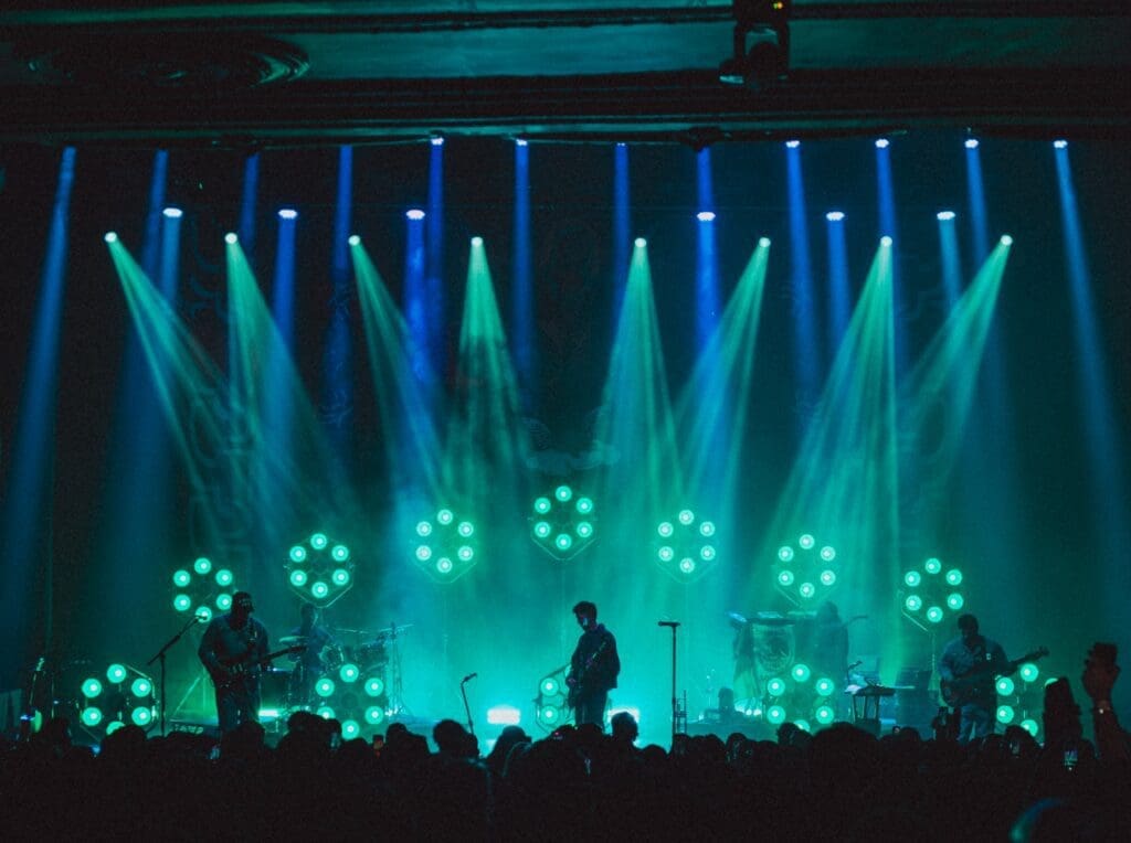 Silhouetted singer performing on stage with vibrant green and blue lighting.