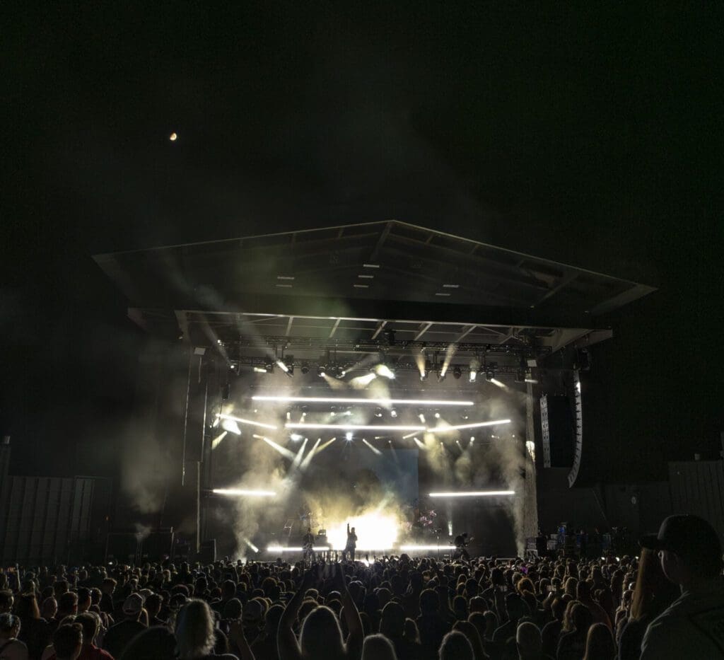 Crowd enjoying a night concert with bright stage lights.
