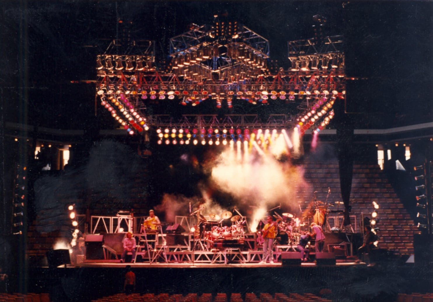 A rock band performing on a large, illuminated stage with smoke effects.