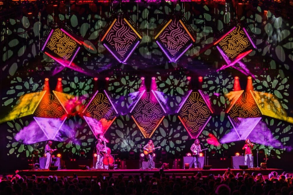 A vibrant stage with colorful geometric and floral light projections.