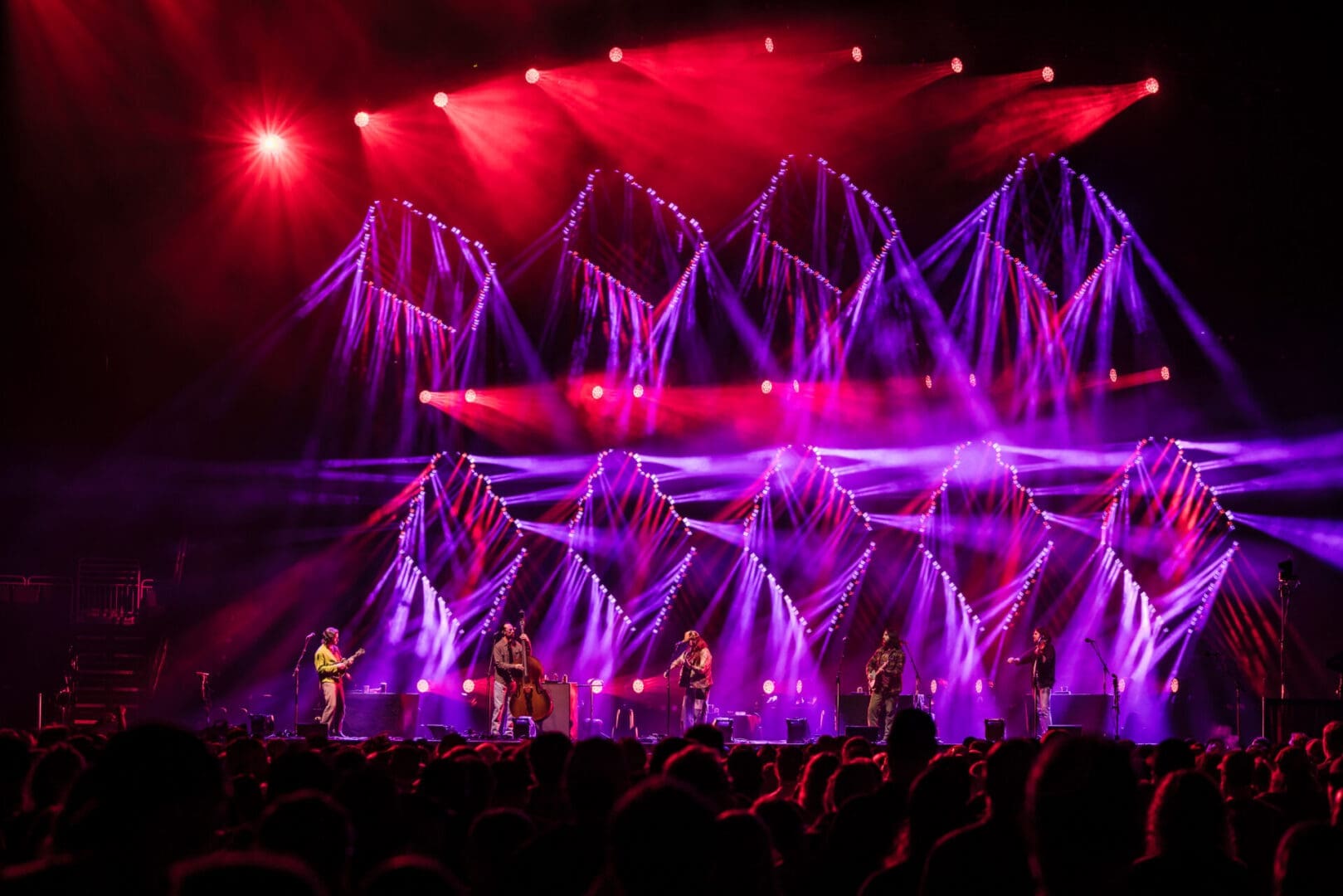 Band performing on stage with vibrant purple and red lights.