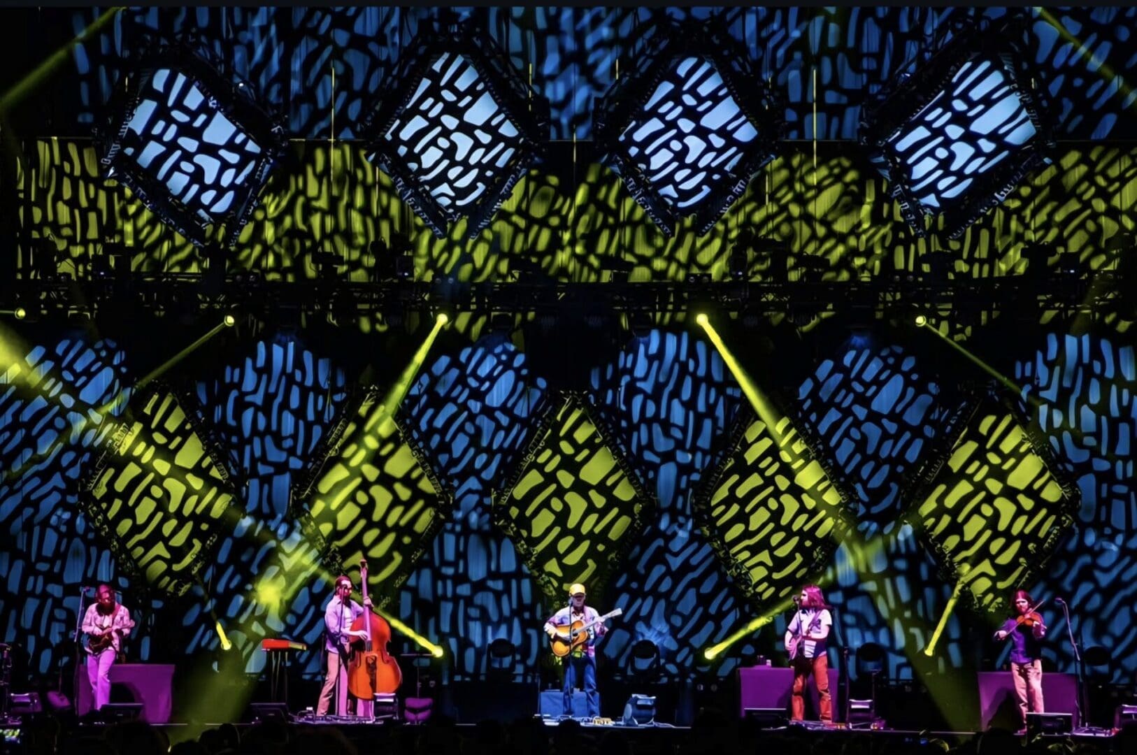 Band performing live with vibrant, geometric stage lights.