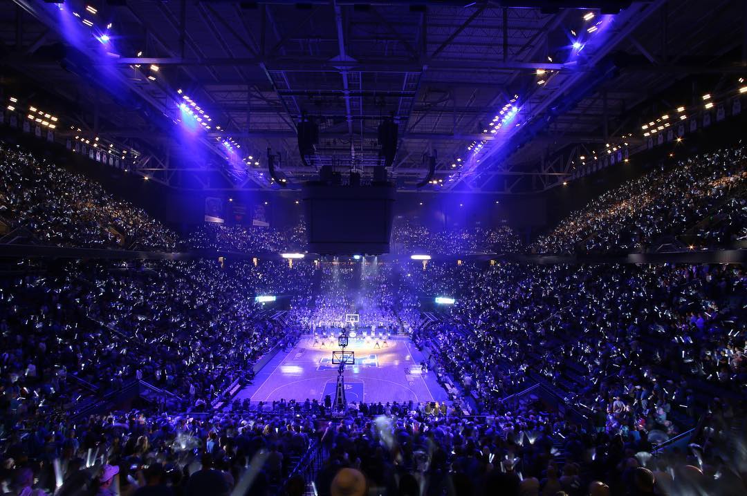 A packed arena with purple lighting during a live event.