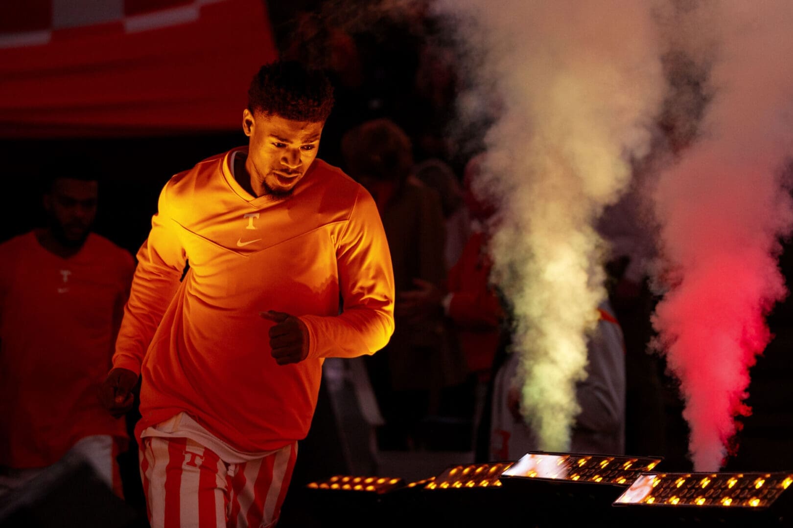 Man lighting candles with smoke rising in a dimly lit setting.