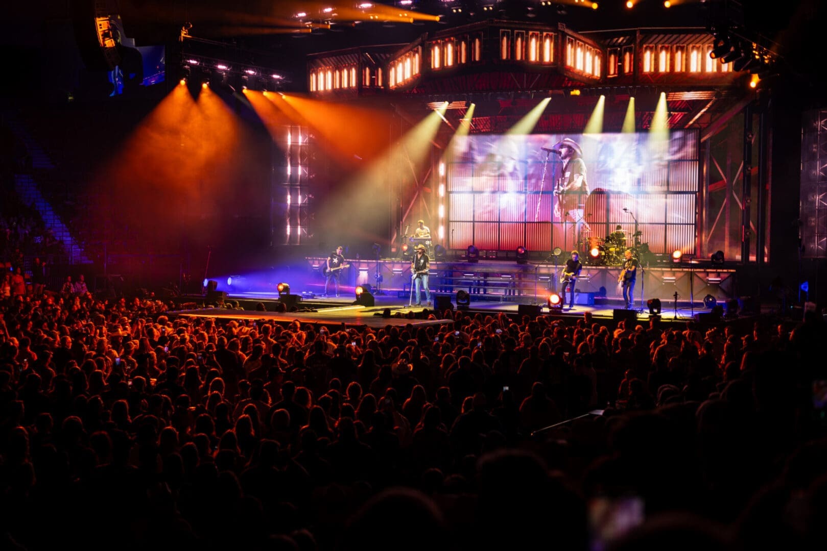 A vibrant live concert with bright stage lights and a large audience.