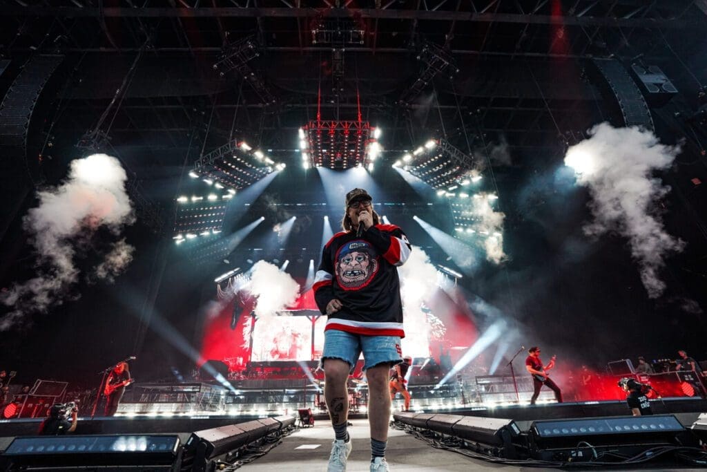 A performer on stage with dynamic lighting and smoke effects at a concert.