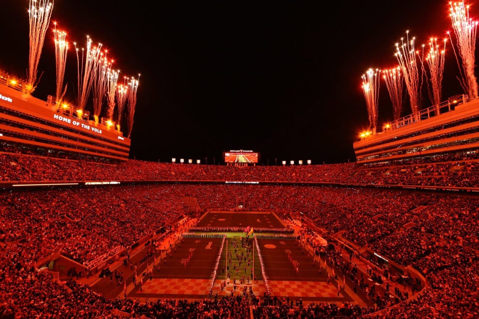 A football stadium illuminated with vibrant red lights during a night game.