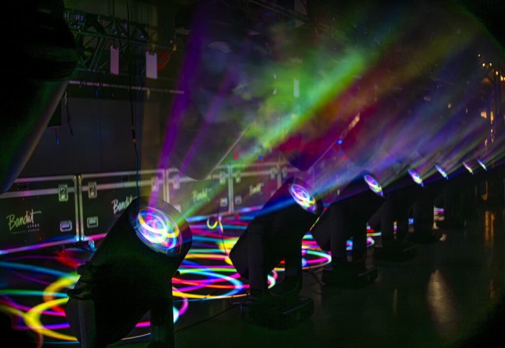 Colorful stage lights creating vibrant beams in a dark room.