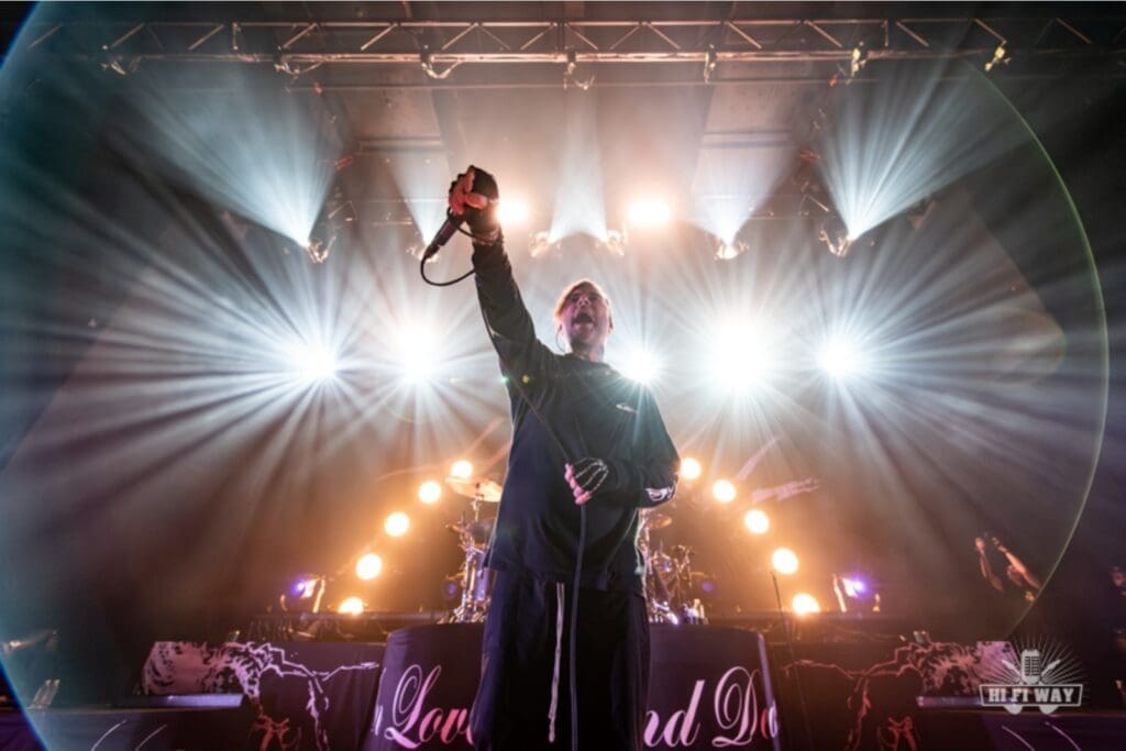 Vocalist passionately performing on stage with dramatic lighting.