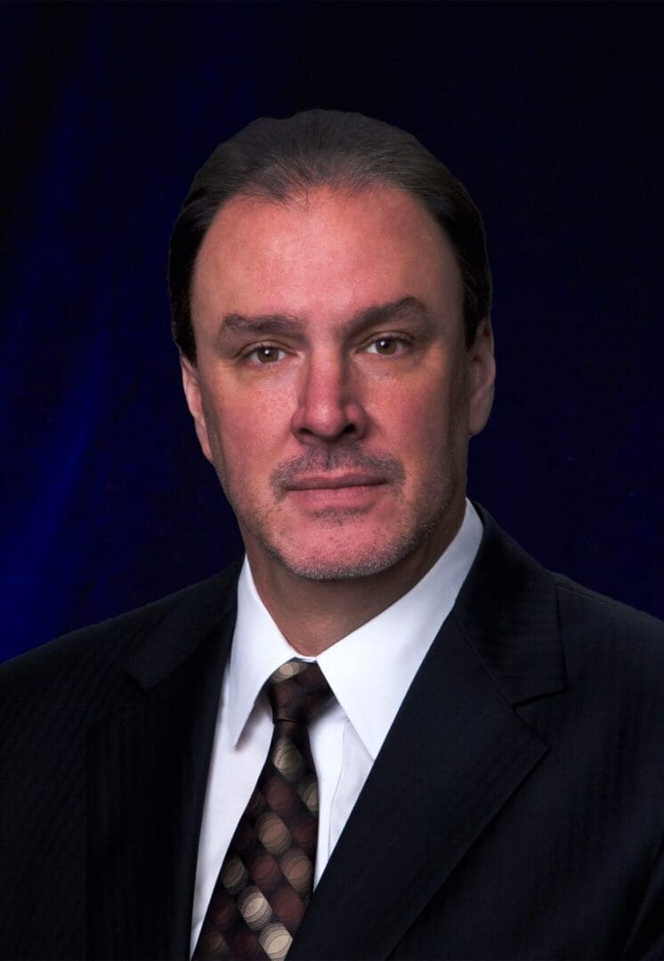 Professional man in a suit against a dark background.