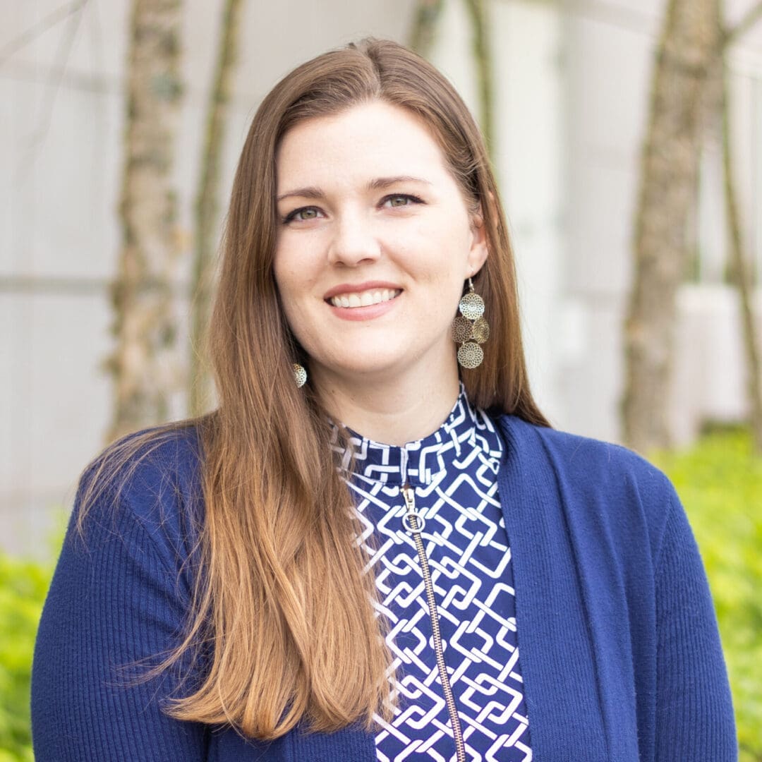 Professional woman smiling outdoors in business attire.