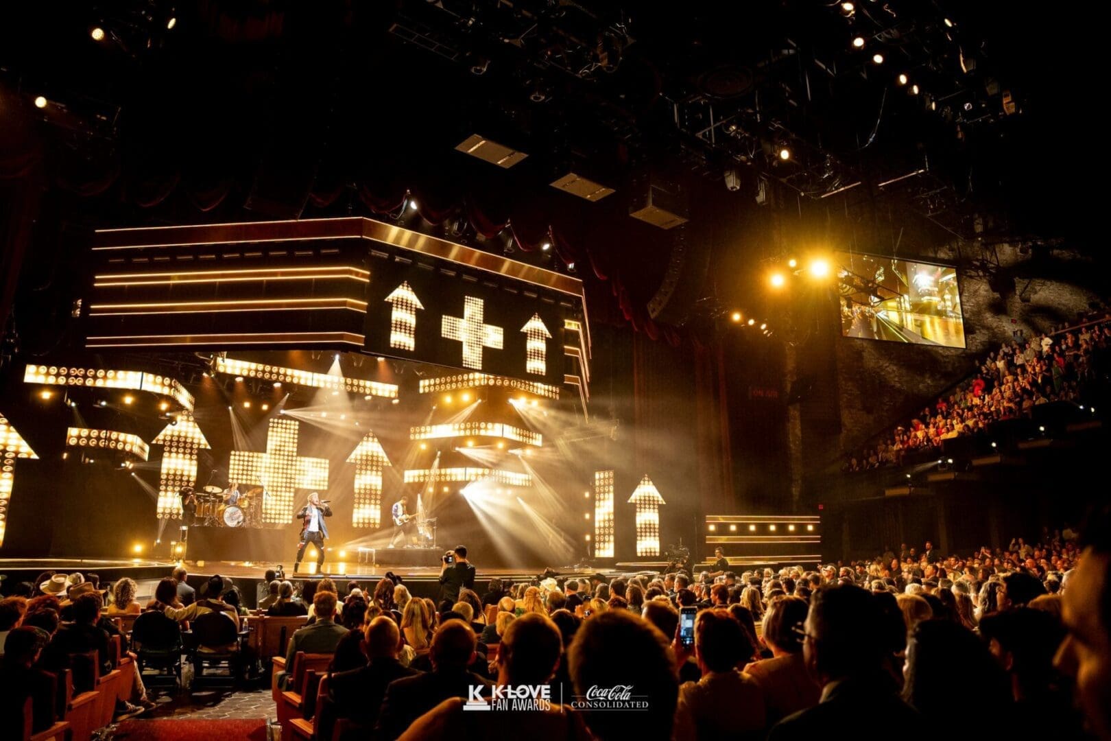 A large crowd enjoying a vibrant concert with bright stage lights.