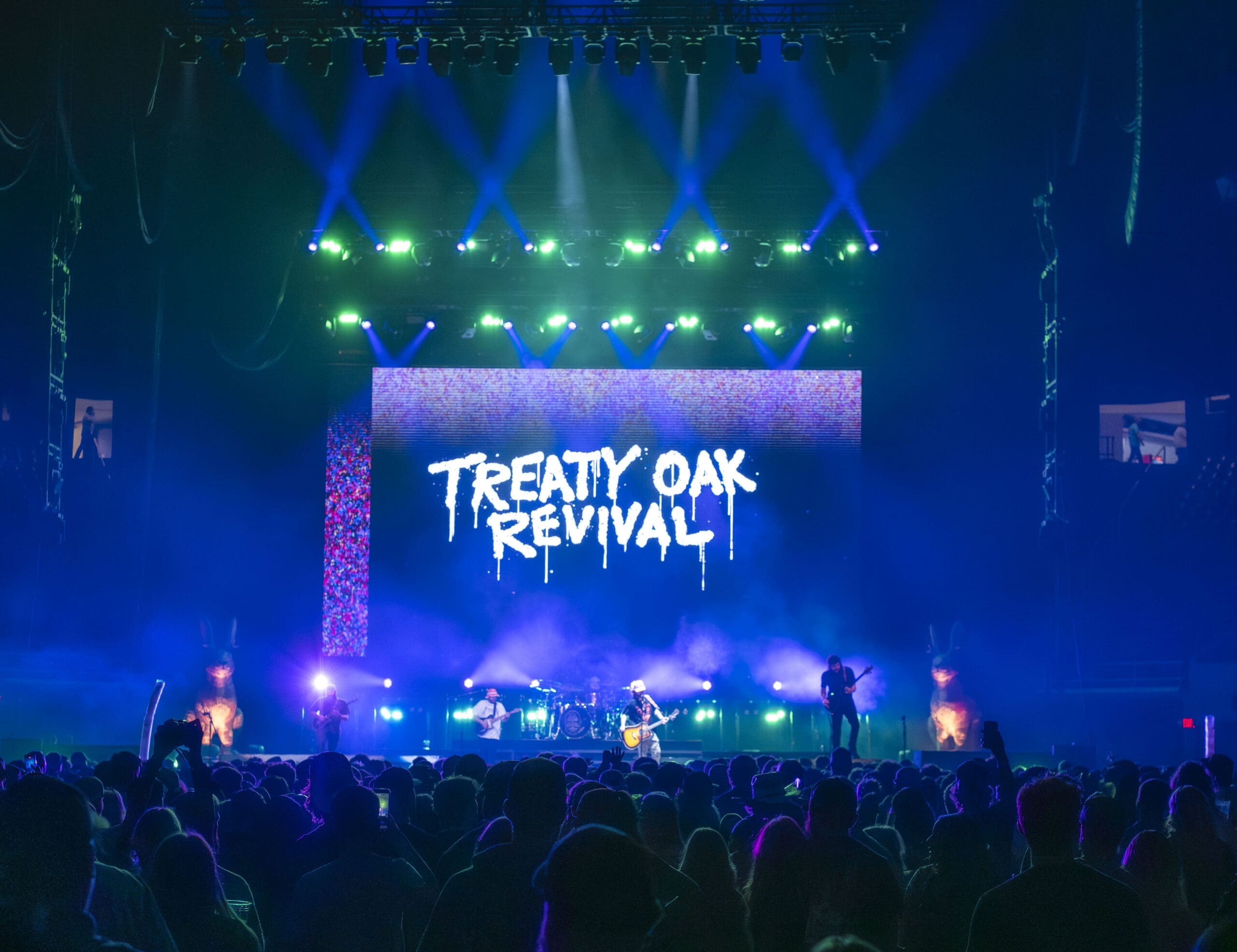A live concert with vibrant lighting and Treaty Oak Revival on the screen.