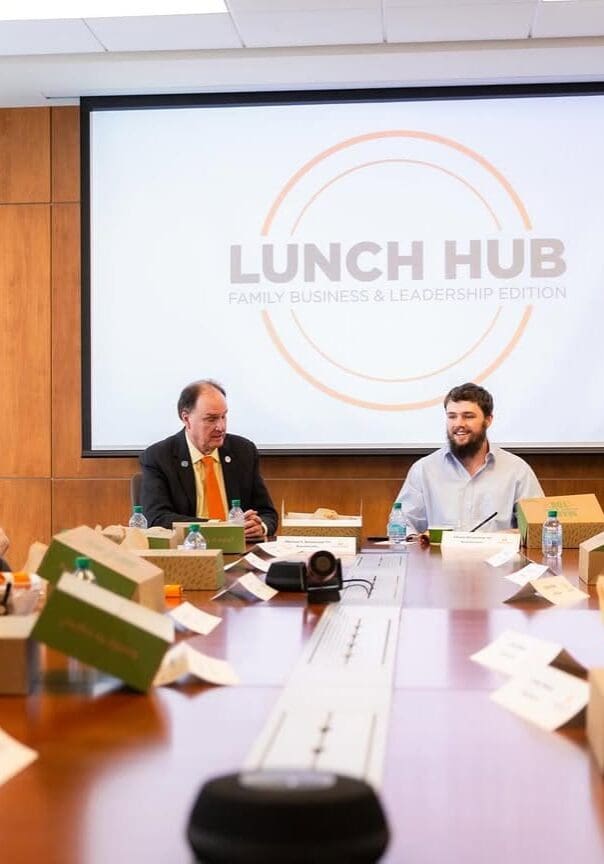 People gather around a table for a Lunch Hub meeting with meal boxes.