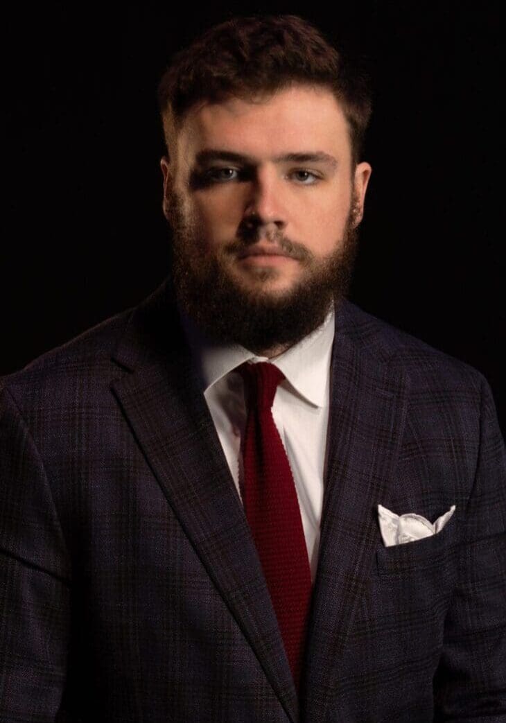 Man in a formal suit with a red tie and pocket square.