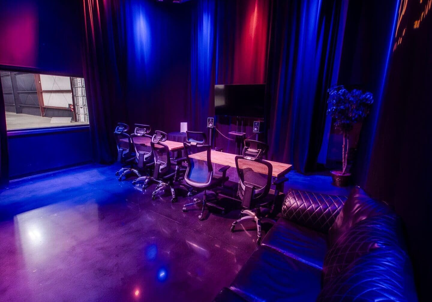 Dimly lit lounge with musical instruments and cozy seating under blue and purple lights.