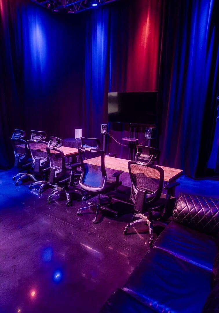 Dimly lit lounge with musical instruments and cozy seating under blue and purple lights.