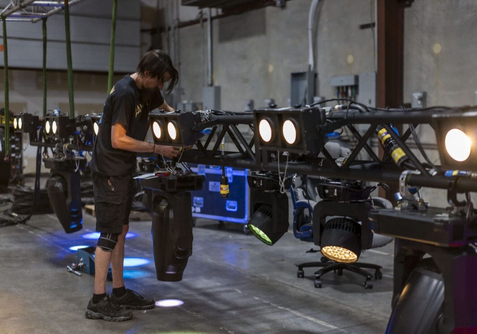 Technician adjusting stage lighting equipment in a warehouse.