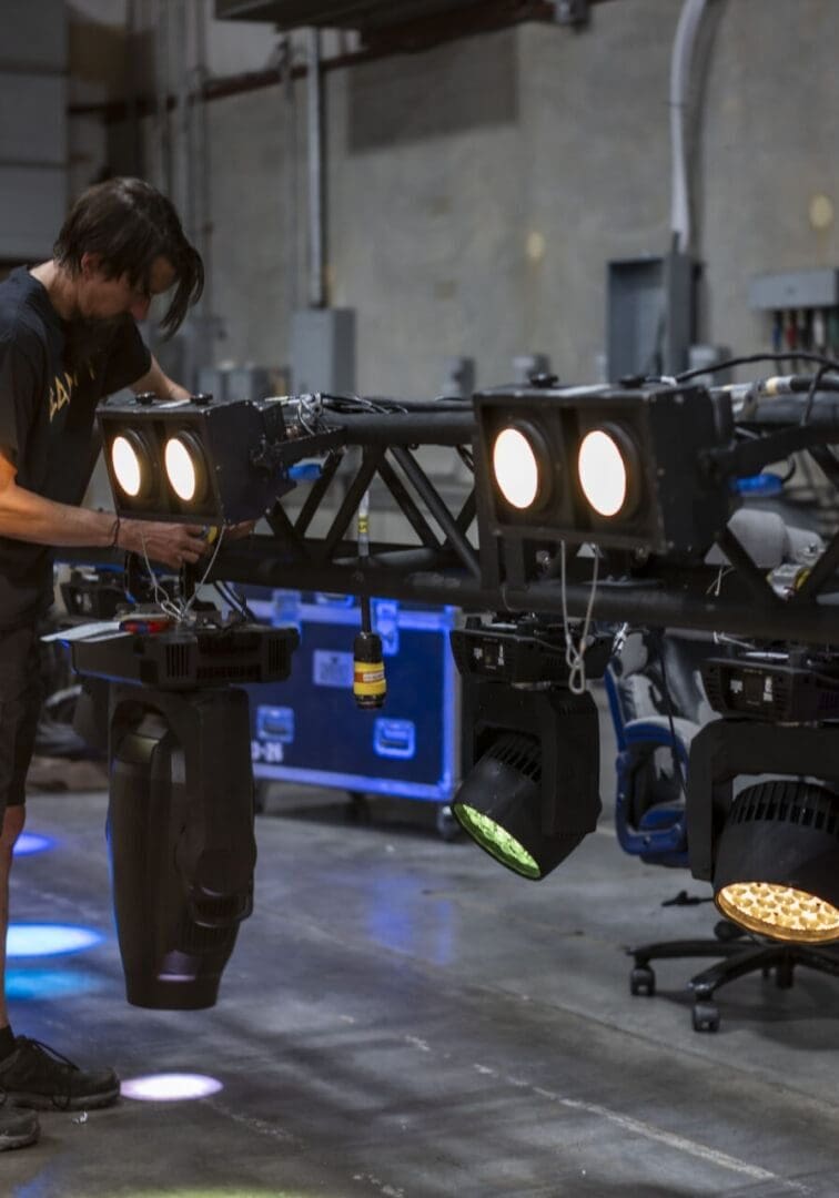 Technician adjusting stage lighting equipment in a warehouse.