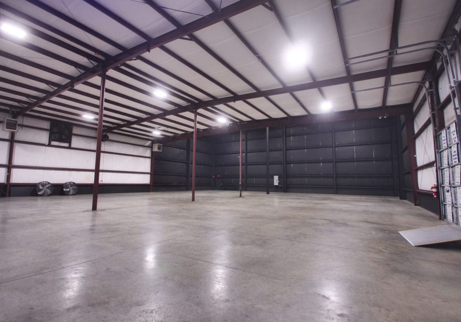 Empty industrial warehouse with polished concrete floor and metal beams.