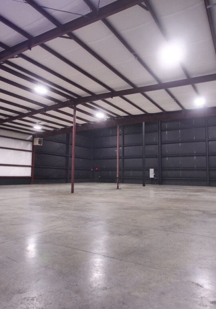 Empty industrial warehouse with polished concrete floor and metal beams.