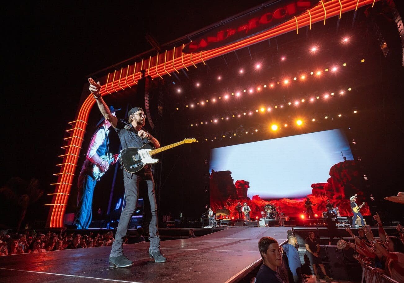 Electric guitarist performing on stage under bright lights.
